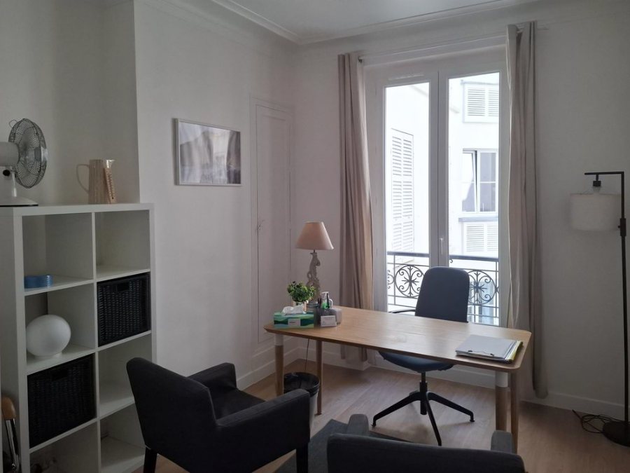 Le cabinet : bureau clair avec fauteuils, fenêtre et bibliothèque